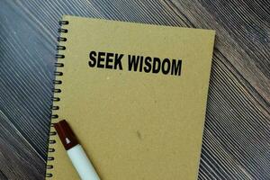 Concept of Seek Wisdom write on sticky notes isolated on Wooden Table. photo
