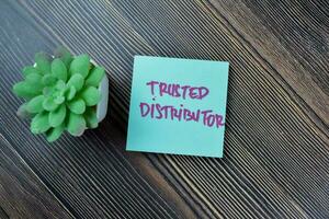 Concept of Trusted Distributor write on sticky notes isolated on Wooden Table. photo