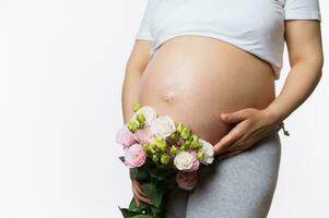 belleza de cerca retrato grávido expectante madre participación ramo de flores de flores cerca su embarazada barriga, aislado en blanco foto