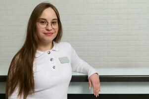 Smiling young receptionist standing at the reception desk in modern medical clinic, dentistry office or beauty spa salon photo