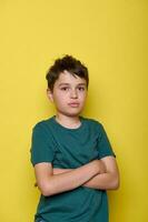 emocional retrato de un triste, abrumado colegio chico expresando triste emociones, con brazos doblada en amarillo antecedentes foto