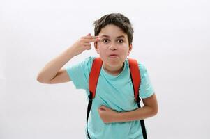 Teen schoolboy pointing two fingers at his temple, showing a shooting gun hand gesture, feeling stress, puberty problems photo