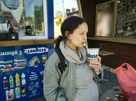 contento multiétnico embarazada mujer Bebiendo con hielo café con azotado crema. Ucrania zaporozhye 2023 foto