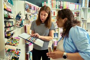 Pleasant woman seller holding metal case with watercolor paints in removable refills, helping customer to choose paints photo