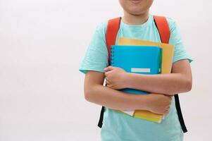 Close-up schoolboy's hands hold textbooks and workbook, isolated white studio background. Copy space. Education concept photo