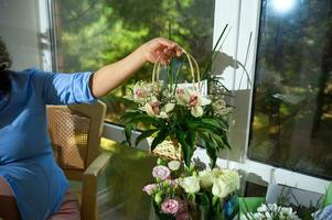 Close-up flower bouquet in florist's hands. Floral design studio. Gifts and arrangements photo