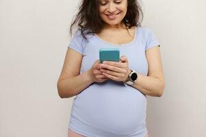 Happy pregnant woman using mobile phone, sharing pregnancy and maternity lifestyle on social media, isolated background photo