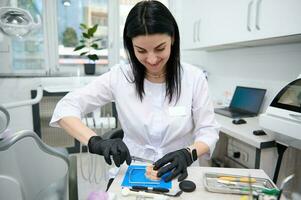 Female dentist doctor, orthodontist, dental engineer enjoying his professional occupation, working with prosthetic photo