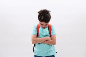 Offended upset schoolboy, folding arms, looking down after act of bullying at school, isolated on white background photo