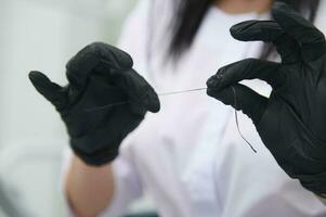 Close-up dental floss in hands of doctor dentist hygienist in black surgical gloves. Dental health. Oral hygiene concept photo