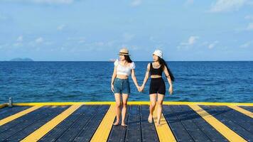 Two women friends or couples relaxing in the sea and walking at tropical beach travel summer holidays. Female tourists enjoy traveling to exotic nature in their leisure time. Friendship concept photo