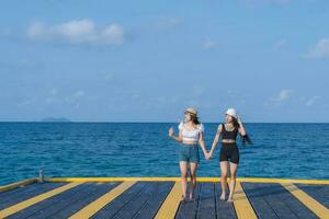 Two women friends or couples relaxing in the sea and walking at tropical beach travel summer holidays. Female tourists enjoy traveling to exotic nature in their leisure time. Friendship concept photo