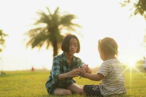 Silhouette of two cute little girls sitting on the grass at the backyard during a beautiful golden yellow sunset. photo