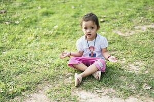 Little asian girl practicing mindfulness meditation outdoor in a park. photo