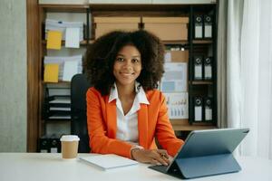 African businesswoman working in the office with working notepad, tablet and laptop documents photo
