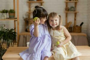 little happy girls fool around in the kitchen and eat apples photo