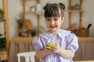 a little beautiful girl in a bright dress is fooling around in the kitchen photo