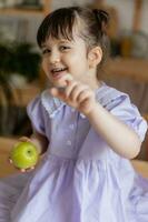 a little beautiful girl in a bright dress is fooling around in the kitchen photo