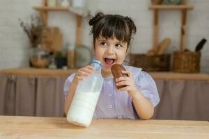 a little beautiful girl in a bright dress is fooling around in the kitchen photo