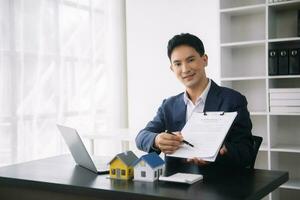 Asian man working with House model real estate agent and customer discussing for contract to buy house, insurance or loan real estate consult concerning mortgage loan offer photo