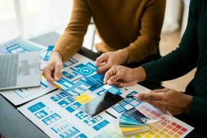UX developer and ui designer brainstorming about mobile app interface wireframe design with customer breif and color code at modern office. photo
