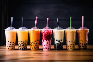 Plastic cups of different tasty bubble tea. Row of fresh boba bubble tea glasses. photo