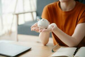 Women are putting coins in a piggy bank for a business that grows for profit and saving money for the future. planning for retirement concept photo