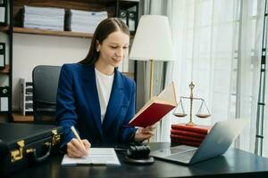 Female judge in a courtroom  the gavel, working with smart phone and laptop and digital tablet computer on wood table photo