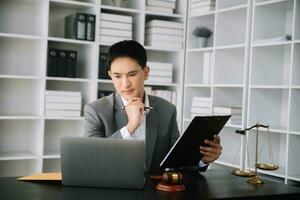 Attractive young lawyer in office Business man and lawyers discussing contract papers laptop and tablet with brass scale on  desk in office. photo
