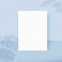 A blank white paper sheet on light blue background with a shadow overlay. The papers mock-up. photo