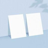 dos vacío blanco papel hojas en ligero azul antecedentes con sombra cubrir. foto