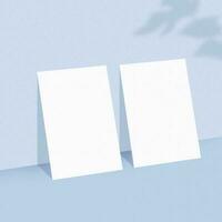Two empty white paper sheets on light blue background with shadow overlay. photo