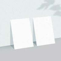 Two empty white paper sheets on light background with shadow overlay. photo