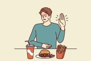 Man suffering from gastritis refuses fast food that causes pain in abdomen on advice of nutritionist. Guy near table with junk lunch shows stop gesture due to gastritis caused by eating hamburgers vector