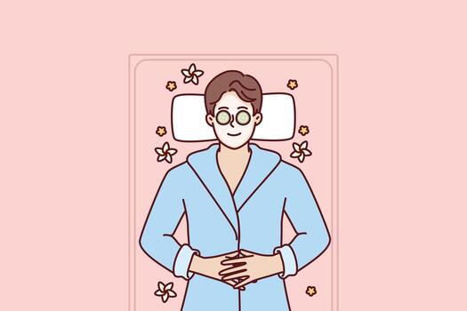 Man with clay mask on face lies in SPA during rejuvenation and anti-wrinkle treatment. Guy with cucumbers on eyes smiles being in SPA salon and restoring strength after hard day work vector