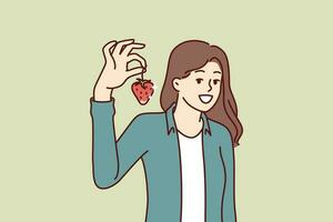 Woman with strawberries smiles recommending eating fresh organic fruits containing healthy vitamins. Large strawberry in hand of beautiful girl showing off good harvest of berries. vector