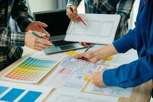 UX developer and ui designer brainstorming about mobile app interface wireframe design with customer breif and color code at modern office. photo