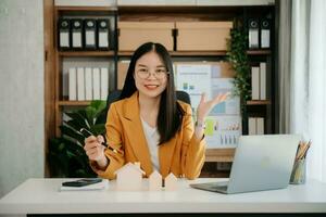 Confident Asian woman with a smile standing holding notepad and tablet at the office. photo