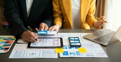 UX developer and ui designer brainstorming about mobile app interface wireframe design with customer breif and color code at office. photo