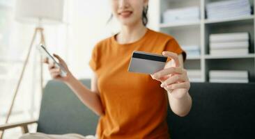 Asian woman hands using smartphone and holding credit card sitting. Online Shopping payments concept. photo