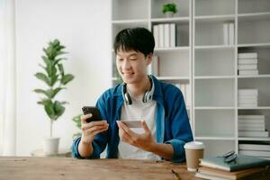 Man using smart phone for mobile payments online shopping,omni channel,sitting on table,virtual icons graphics interface screen in morning light photo
