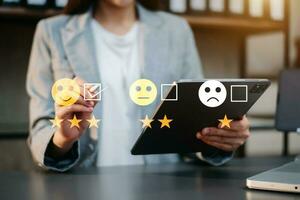 concepto de evaluación del servicio al cliente. mujer de negocios presionando el espectáculo de emoticonos de sonrisa en la pantalla virtual en la tableta y el teléfono inteligente foto