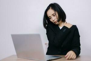 Concept Office Syndrome, Young Asian female office worker is tired from hard work, shoulder pain due to working hours consecutively. photo