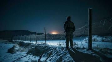 A solitary soldier standing guard at a border post during a frosty winter night photo