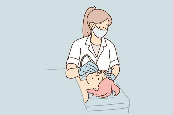 Woman cosmetologist performs microdermabrasion procedure or mechanical peeling and diamond face polishing. Girl visits beautician to get rid of wrinkles or clear skin of acne and pimples