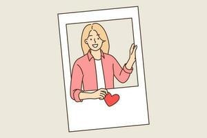 Portrait of girl peeking out of photo frame and holding heart in hand symbolizing love for boyfriend. Happy girl looking at screen declaring love to guy or posing for romantic valentine vector