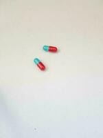 Isolated white photo of two blue and red medicine capsules.