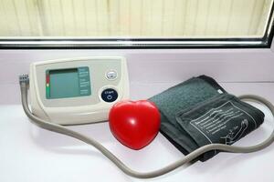 automatic portable blood pressure monitor - turned off device and rubber hand trainer in the shape of a heart photo