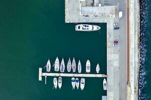 Top View by drone of yachts and small motor boats on the harbor. Yacht and sailboat are moored at the quay. photo