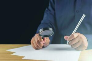 The man creates new idea by magnifying glass and pen. Research and development concept. photo